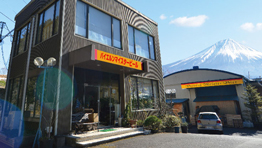 富士山を背景にした黒い建物とオレンジの看板がある風景。