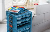 積み重ねられた青い工具箱と、近くにネジや壁のプラグが入った開いた整理トレイ。