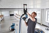 安全装備を身に着けた人が、集塵システム付きの天井に穴を開けています。