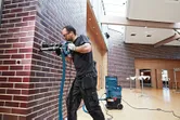 安全装置を装着した人が、システム付属のツールを使用してレンガの壁に穴を開けます。.
