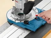 精密な木工作業のために、金属製のガイド レール上で青いルーター ツールを調整する人。