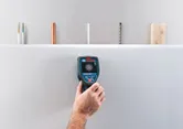 人が壁スキャナー検出器を使用して乾式壁の表面の裏側を確認します。