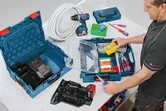 作業台の上の青い工具ケースにネジと手工具を整理している人。