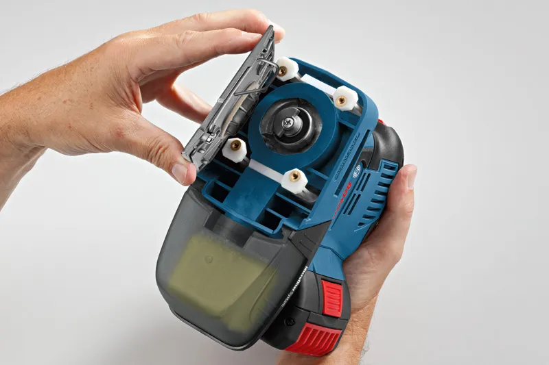 コードレスオービタルサンダーのサンディングパッドを交換している人。.