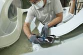 安全装備を身に着けた人がコードレスマルチツールでグラスファイバーを切断しています。