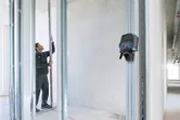 建設中の建物内で、レーザーレベルツールアクセサリを使用して金属フレームの位置合わせをしている人。