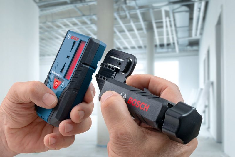 LR 6、LR 7用受光器ホルダー 建設中の建物内で、レーザー測定器とブラケットを組み立てている人。.