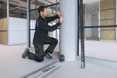 安全装備を身に着けた人がレーザーレベル測定ツールを使用してコンクリートの柱に印を付けています。