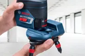 明るい未完成の部屋で、レーザーレベルツールのアクセサリを調整する人。