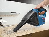 コードレス掃除機を使用して作業台からゴミを拾っています。