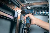 コードレスインパクトレンチを使用して、電気パネル内のボルトを締めます。