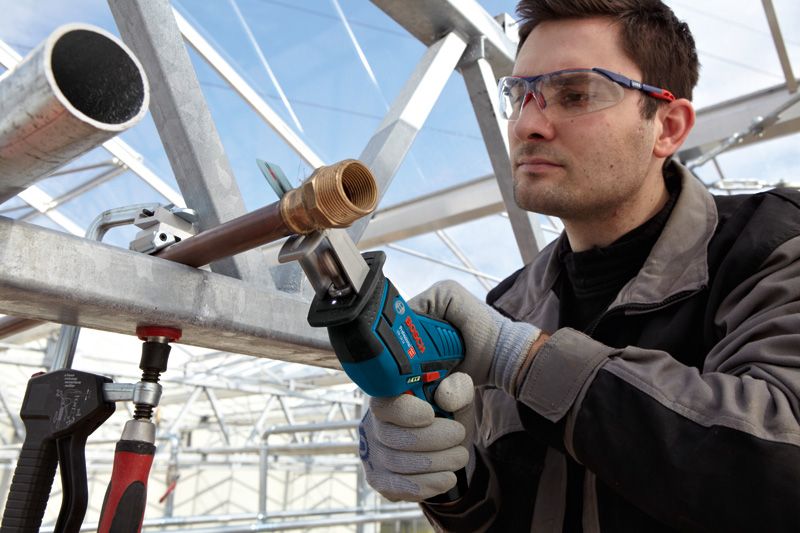 安全装置を装着した人がレシプロソーで金属パイプを切断しています。