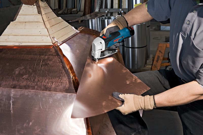 安全装置を装着した人がコードレス金属鋏で金属板を切断します。.