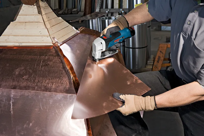 安全装置を装着した人がコードレス金属鋏で金属板を切断します。.