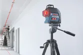 レーザーレベルツールは、はしごの上で作業する人が天井に赤い線を投影します。