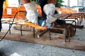 安全装備を身に着けた人が建設現場でアングルグラインダーを使用して鉄筋を切断しています。