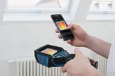 人がサーモカメラとスマートフォンを使用して、屋内で熱画像を閲覧しています。