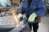 安全装置を装着した人がアングルグラインダーで金属を研磨し、火花を発生させます。