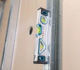 金属スタッドと乾式壁パネルの垂直位置合わせを測定する水準器。