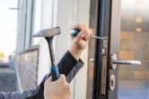 ハンマーとドライバーを使用してドアロック機構を取り付ける人。