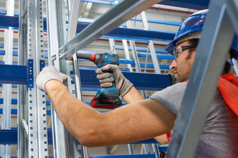安全装置を装着した人が金属フレームのコードレスドリルを使用しています。.