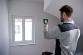 建物内の窓部分をサーモカメラでスキャンする人。