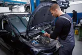 安全装備を身に着けた人がサーモカメラで車のエンジンを検査しています。
