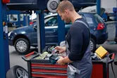 安全装備を身に着けた人が自動車修理工場で作業中にサーモカメラを使用しています。