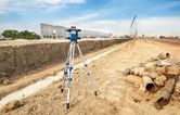 大規模な建設現場に三脚に設置されたレーザーレベル測定ツール。