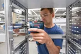 安全装置を装着した人が金属フレーム上でコードレスドライバーを使用しています。.