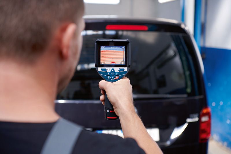 ある人がサーモカメラを使って黒いバンの後部窓をスキャンしています。