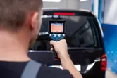 人がサーモカメラを使用して車両の後部窓をスキャンしています。