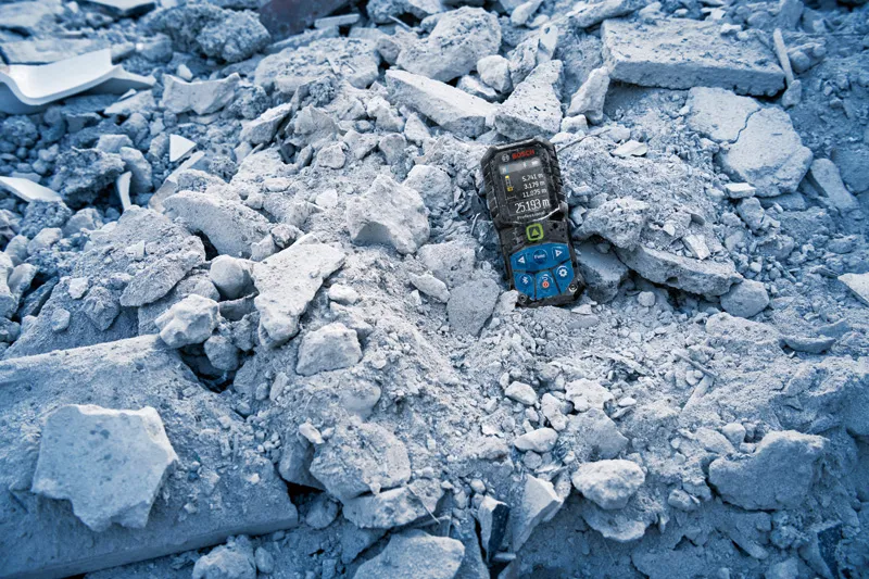 建設廃材に部分的に埋もれたレーザー測定装置。.