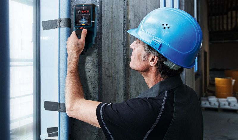 D-TECT 200 JPS 安全装備を身に着けた人が探知機でコンクリートの壁をスキャンします。.
