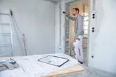 建設現場でレーザー測定器を使用して壁までの距離を確認している人。