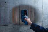 デジタル探知機でコンクリートの壁をスキャンし、内部のパイプや配線を明らかにする人。