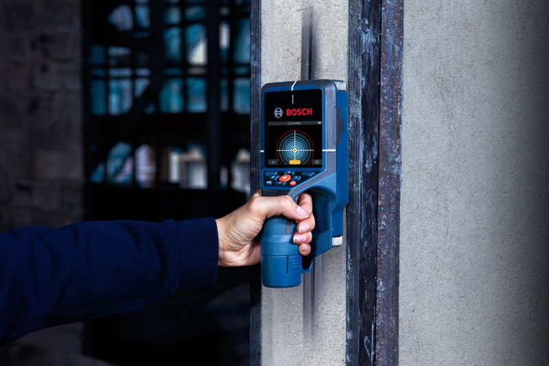 D-TECT 200 JPS 検出器を使用して壁をスキャンし、隠れた物体を探す人。.