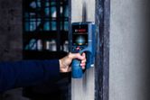 検出器を使用して壁をスキャンし、隠れた物体を探す人。