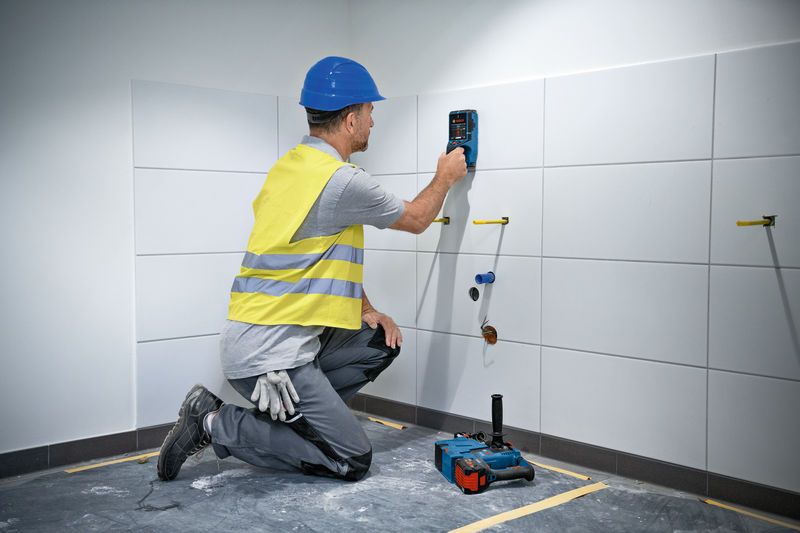 D-TECT 200 JPS 安全装備を身に着けた人がタイル張りの壁で壁スキャナーを使用しています。.