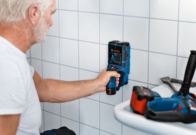 D-TECT 200 JPS 作業スペースで検査ツールを使用してタイル張りの壁をスキャンする人。.