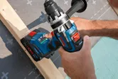 コードレスドリルドライバーを使用して木の梁に作業する人。