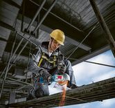 安全装置を装着した人がアングルグラインダーを使用して金属の梁を切断しています。.