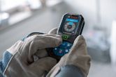 安全装備を装着した人がデジタルディスプレイ付きのレーザー測定器を操作します。