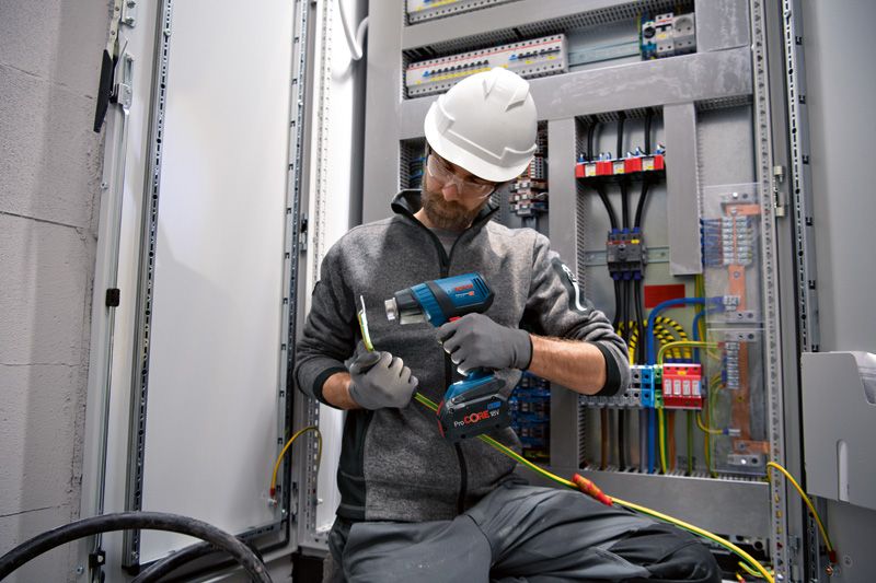 GHG 18V-50 安全装置を装着した人が電気配線にコードレスヒートガンを使用しています。.