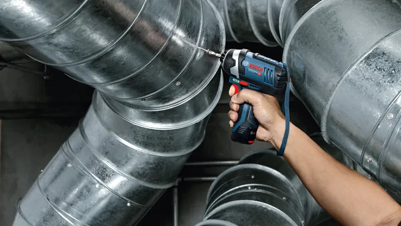 コードレスインパクトドライバーを使用して、金属製のエアダクトにネジを締めています。