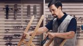 作業場でコードレスドライバーを使用して木片を固定する人。