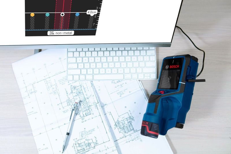 D-TECT 200 JPS コンピューターのキーボードの横にある建築設計図上のデジタル壁スキャナー検出器。.