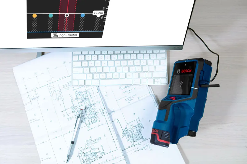 電子検出器が、コンピューターのキーボードの近くの机の上にある技術設計図をスキャンしている。