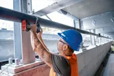 安全装置を装着した人がインパクトレンチを使用して金属パイプを締めます。.