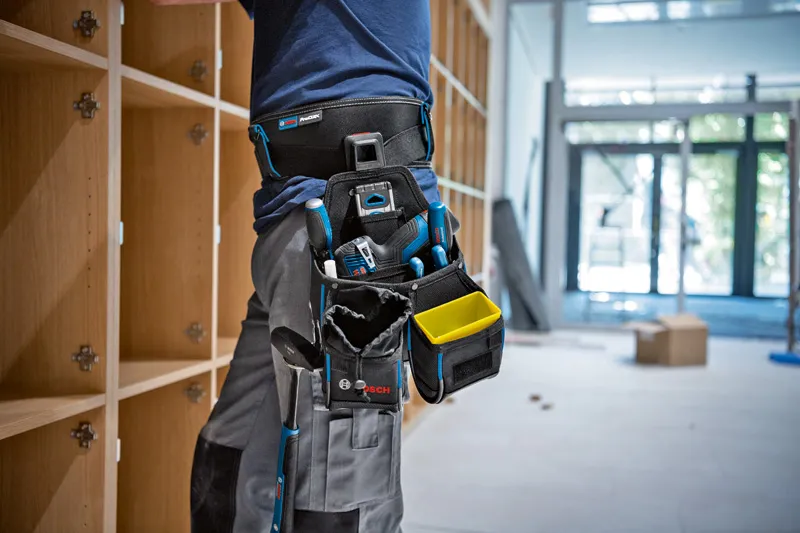 ツールキット:ベルト93 x 1、GWT 2 x 1、GWT 4 x 1、ProClick Holder x 2 安全装備を身に着けた人が、計測ツールを装着したツールベルトを使用して棚を設置します。.
